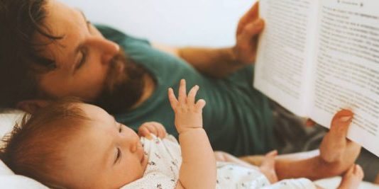 Family father and infant baby reading book fairytale laying on bed at home lifestyle dad and child daughter together parenthood childhood concept Fathers day holiday